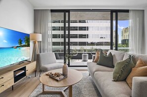Una sala de estar moderna con un televisor grande, un sofá, un sillón y una mesa de centro.