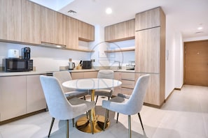 Une cuisine moderne avec des meubles en bois, une table ronde en verre et quatre chaises grises.