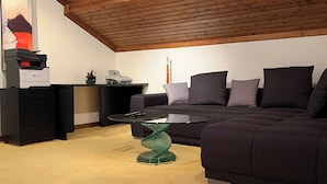 En moderne stue med en mørk sofa, et sofabord i glas og en unik grøn glasfod.