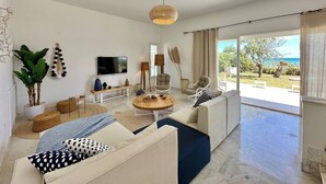 Una sala moderna con televisor, asientos y vistas al exterior.