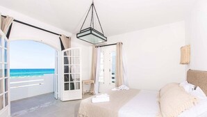 Un dormitorio con cama, lámpara colgante y vista al océano.