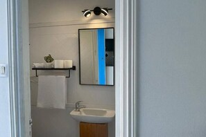 Ein Badezimmer mit einem weißen Waschbecken, einem Spiegel und einem Handtuch an der Wand.