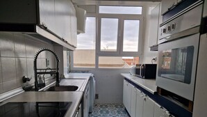 A compact kitchen with a sink, stove, and microwave. - 114m² 3 Bedroom Apartment with Balcony Lift and AC (Nules)
