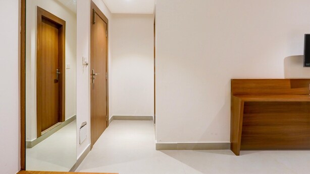 A hallway with a wooden door, a wooden bench, and a wall-mounted TV.