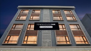 A multi-story building with a sign reading 'TOWNHOUSE OAK' and 'Company-Served.'