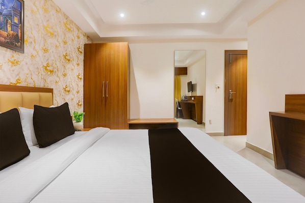 Une chambre d’hôtel avec un lit, une armoire, un bureau et un miroir.