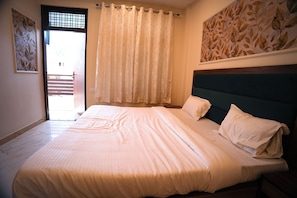 Un dormitorio con una cama, una ventana con cortinas, una puerta y una pared con un diseño de hojas.