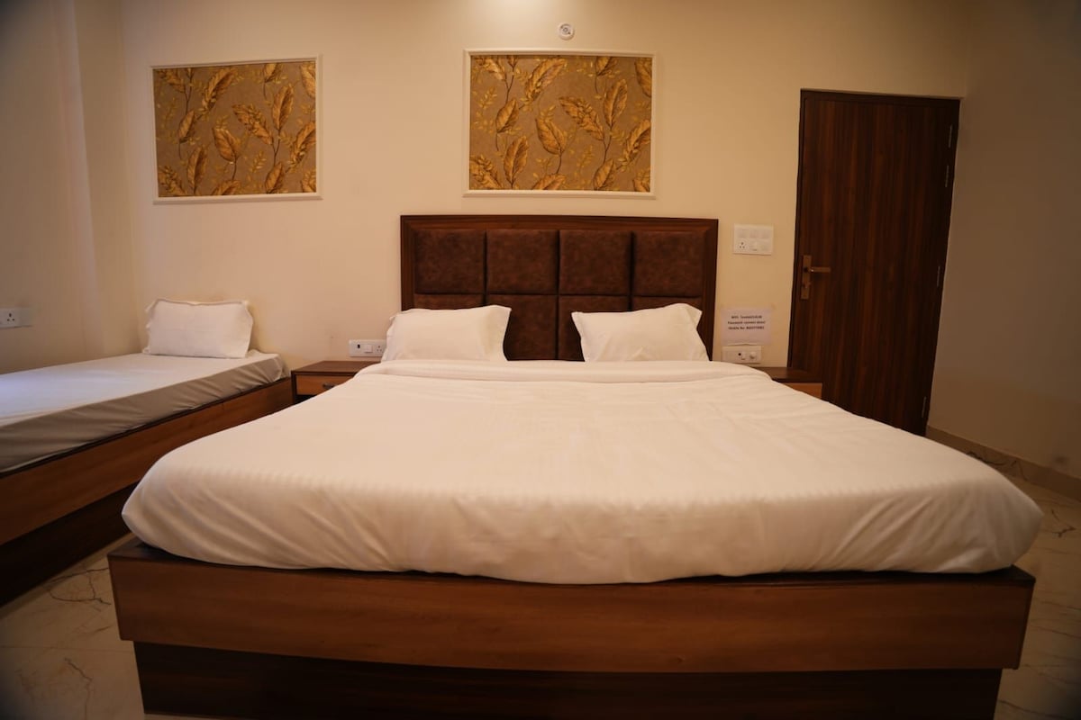 Habitación de hotel con una cama grande, dos mesitas de noche, un cabecero de madera y dos cuadros colgados en la pared.