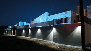 Un bâtiment moderne doté d’une façade en pierre originale et d’une série de lumières verticales illuminées le long de sa base.