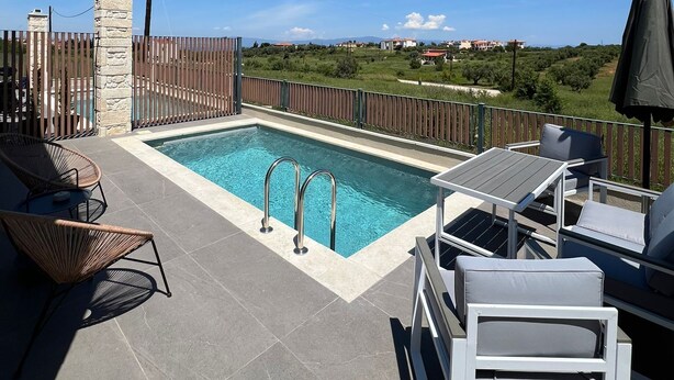 Une piscine sur le toit, avec une eau d’un bleu limpide, entourée d’une clôture en bois, et offrant une vue sur un paysage verdoyant avec des bâtiments qui se dessinent à l’horizon.