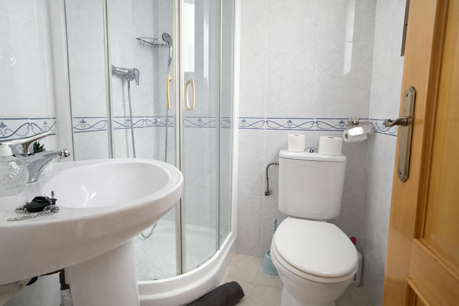 A bathroom with a white sink, a toilet, and a glass-enclosed shower.