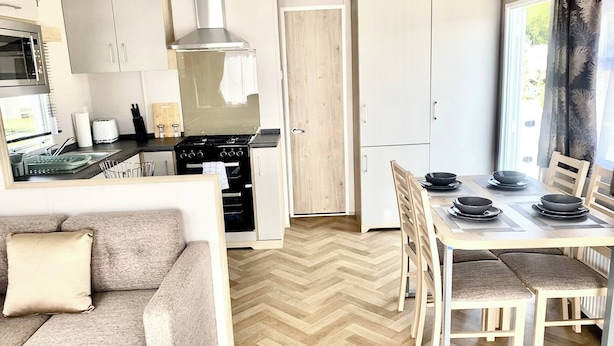 A compact living space with a kitchenette, dining area, and a sofa. - Elegant 2 Bed One and Half Bath Caravan in Holiday Resort - Sleeps 6 (Great Billing)