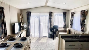A compact living space with a kitchenette, dining area, and a seating area with a view. - Elegant 2 Bed One and Half Bath Caravan in Holiday Resort - Sleeps 6 (Great Billing)
