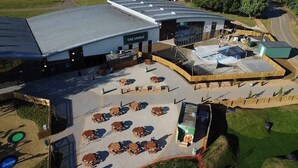 A building with a sign reading 'THE VENUE' and a parking lot with multiple tables and chairs. - Elegant 2 Bed One and Half Bath Caravan in Holiday Resort - Sleeps 6 (Great Billing)