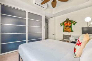 A hotel room with a bed, a desk, a chair, a wall-mounted TV, and a sliding door. - The Palms at Wailea 1805 - Luxury 2BR condo, large lanai, Full AC, Kitchen, WiFi (Kihei)