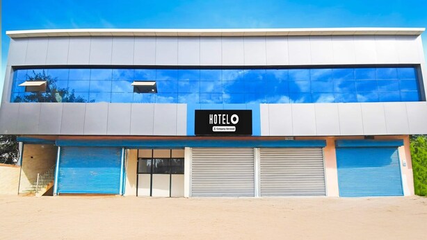 A modern hotel with a large sign reading 'HOTELO Company Serviced.' - Hotel O Mana Camp Near Airport (Raipur)