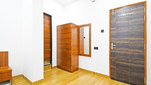 A hallway with wooden flooring, a wardrobe, and a door with a mirror. - Hotel O Mana Camp Near Airport (Raipur)
