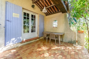 Un porche cubierto con una mesa, sillas, una ventana y una puerta.