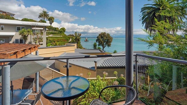 Un balcon avec vue sur la mer, une table ronde et des chaises.