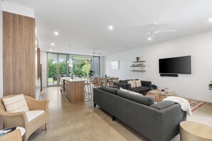 Ein modernes Wohnzimmer mit einer Couch, einem Esstisch und einem an der Wand befestigten Fernseher.