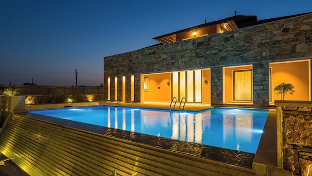 A modern building with a swimming pool, stone facade, and warm lighting. - ELIVAAS The Kanota Retreat 4 BHK Villa (Jaipur)
