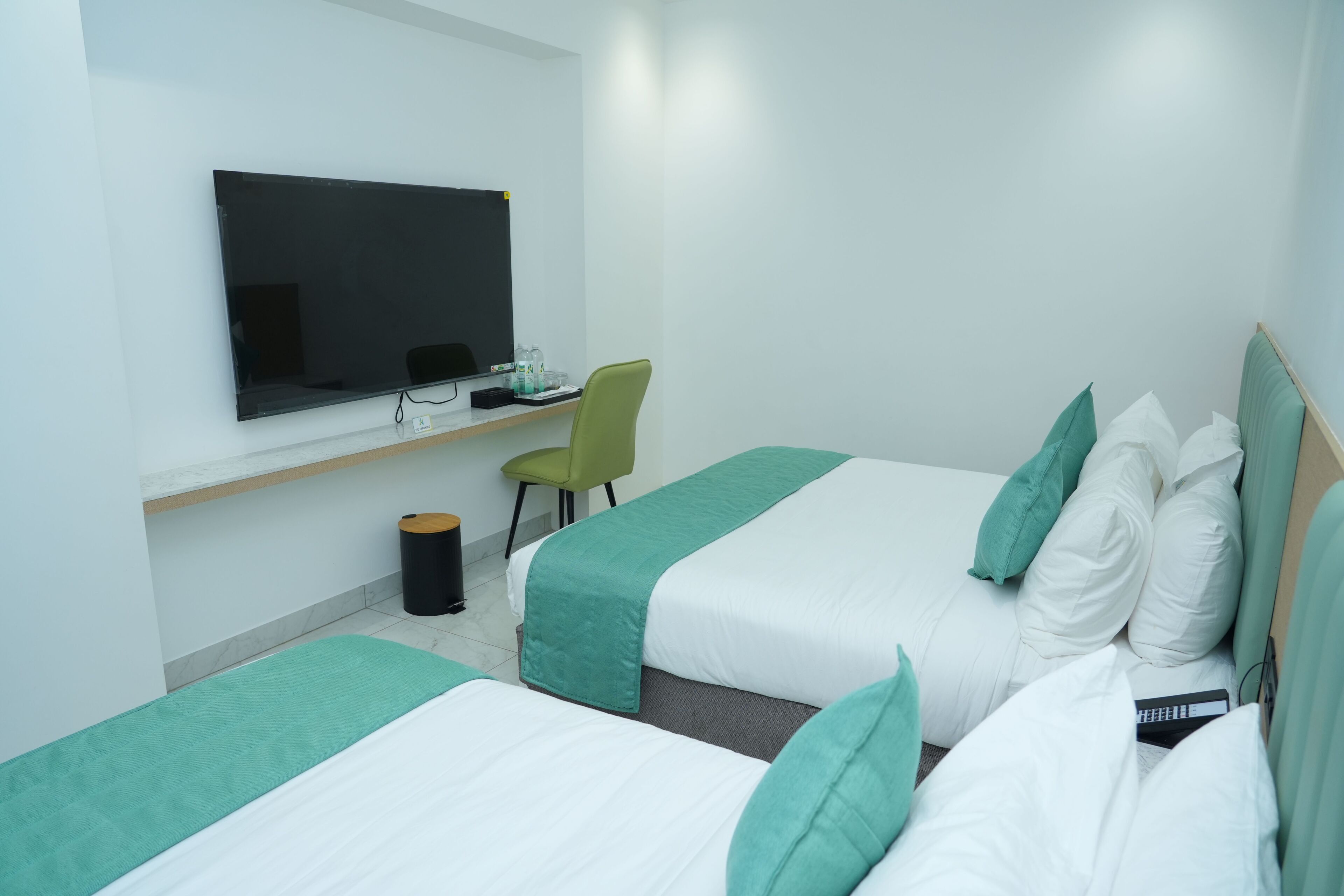 Habitación de hotel con dos camas, un escritorio, una silla y una televisión.