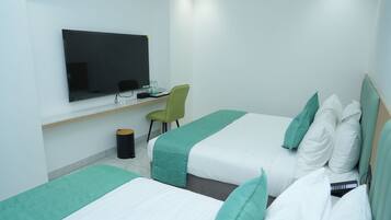 Habitación de hotel con dos camas, un escritorio, una silla y una televisión.