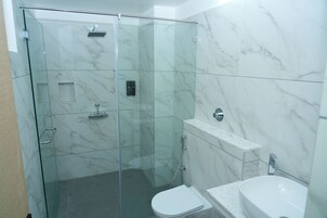 A modern bathroom with a glass shower enclosure, a toilet, and a sink.