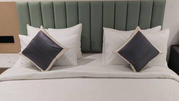 A hotel room with a bed, two pillows, a bedside table with a phone, and a chair.