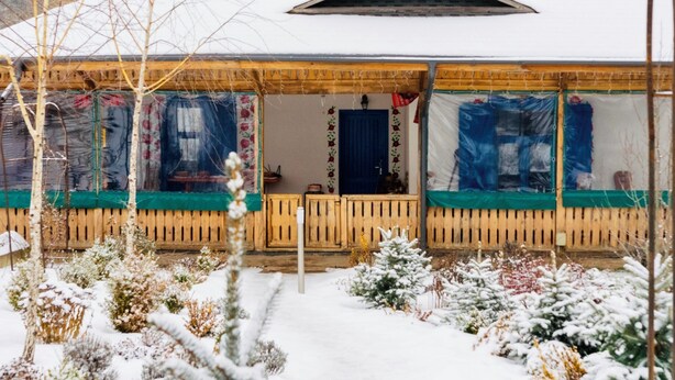 A snow-covered building with a wooden porch and a covered entrance. - Cozy nature escape for relaxation, connection, and memorable stays (Poiana cu Cetate)