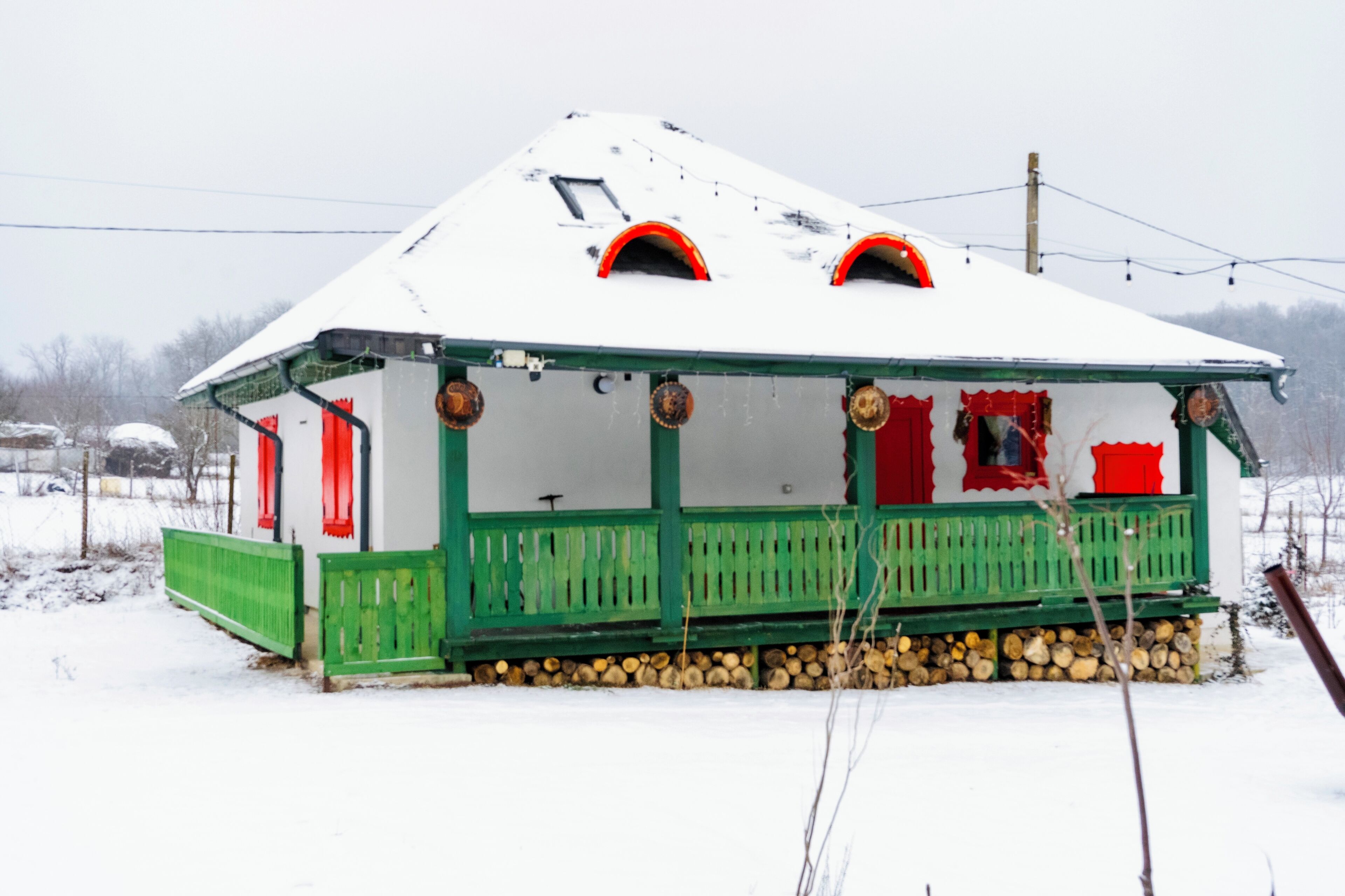 Una casa coberta de neu amb un porxo verd i detalls vermells.
