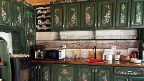 A kitchen with green cabinets, a microwave, a coffee machine, and a red sink. - Cozy nature escape for relaxation, connection, and memorable stays (Poiana cu Cetate)