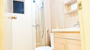 A bathroom with a toilet, a shower, and a sink.