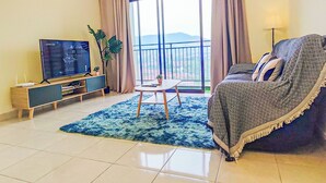 A living room with a TV, sofa, coffee table, and a view of the outdoors.