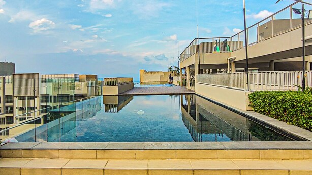 A modern building with a glass pool and a clear sky.