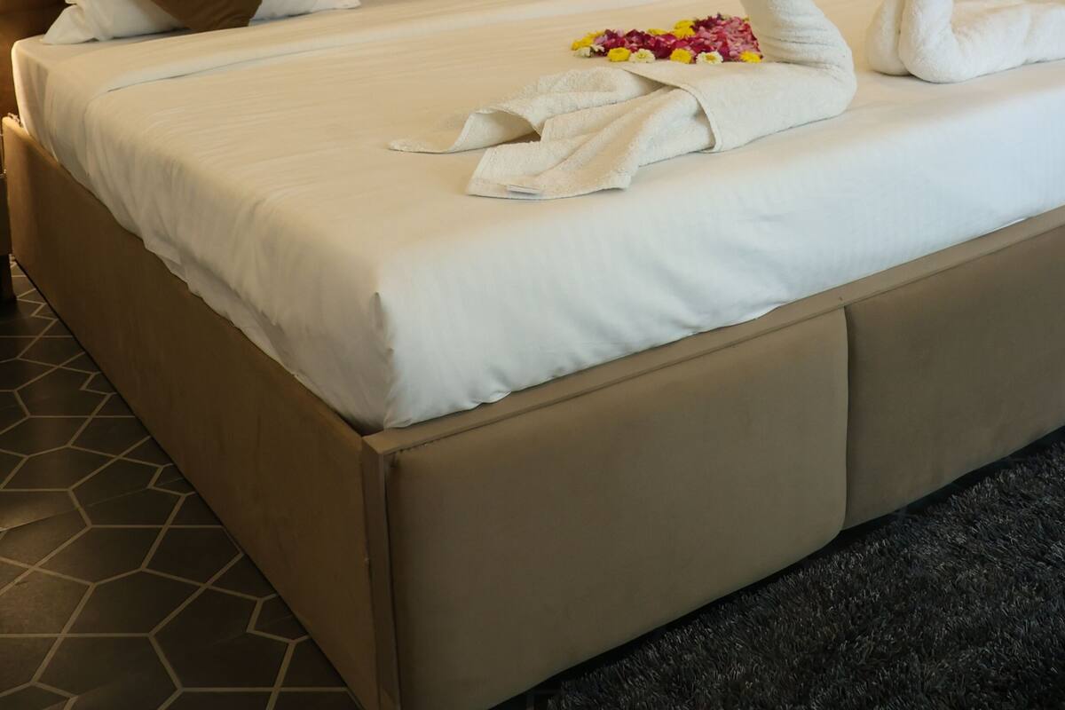 Una habitación de hotel con una cama grande, cabecera y pared con estampado floral.