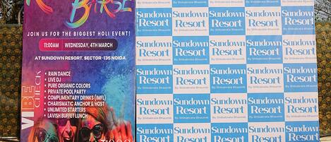 A promotional banner for a Holi event at Sundown Resort, featuring a vibrant design and event details.