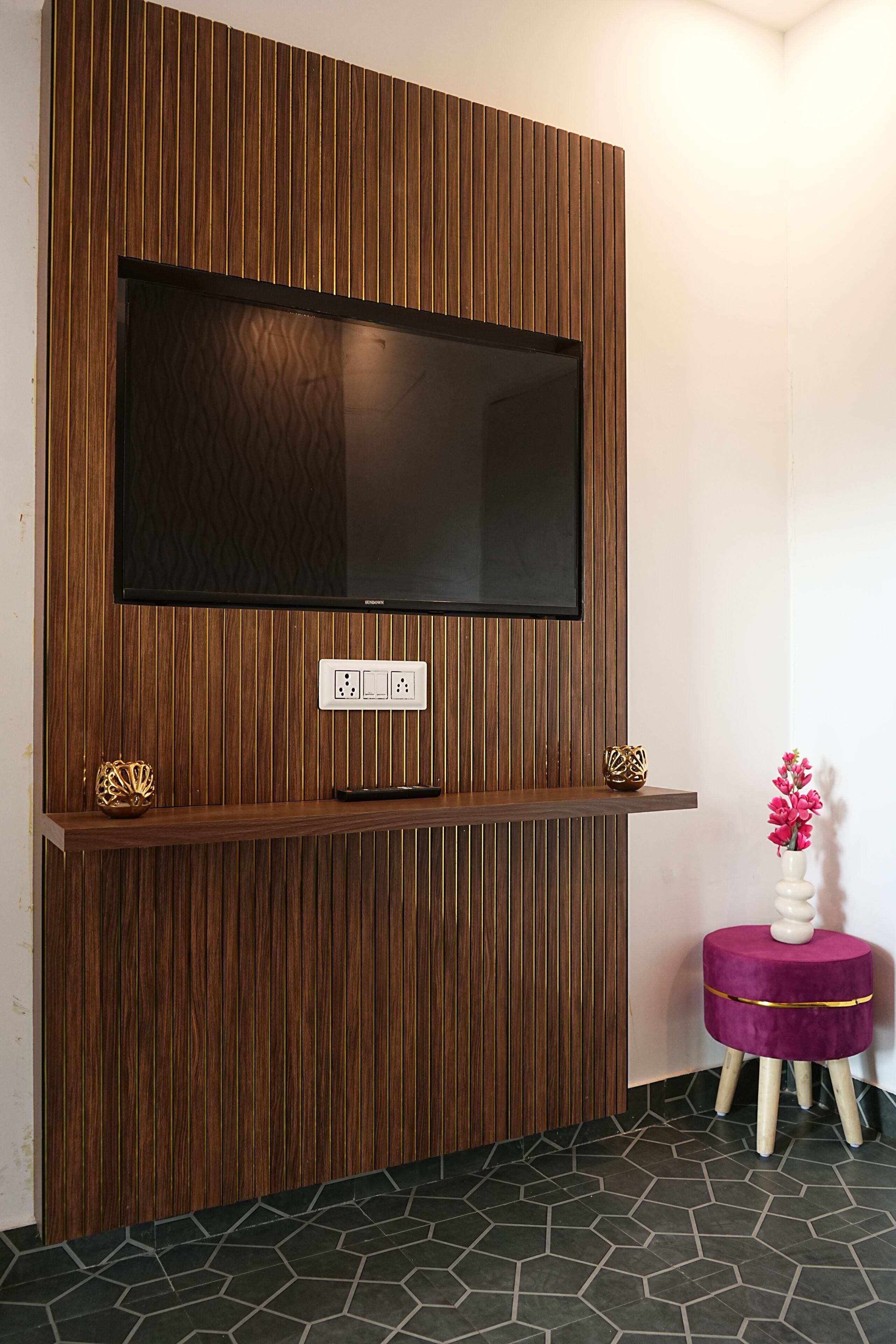 A flat-screen TV mounted on a wooden wall with a power outlet below it.
