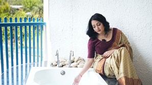 A person sitting by a bathtub with a white wall and a blue fence in the background. - Sundown Resort (Noida)