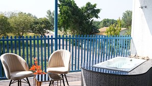 A balcony with two chairs, a table, and a hot tub. - Sundown Resort (Noida)
