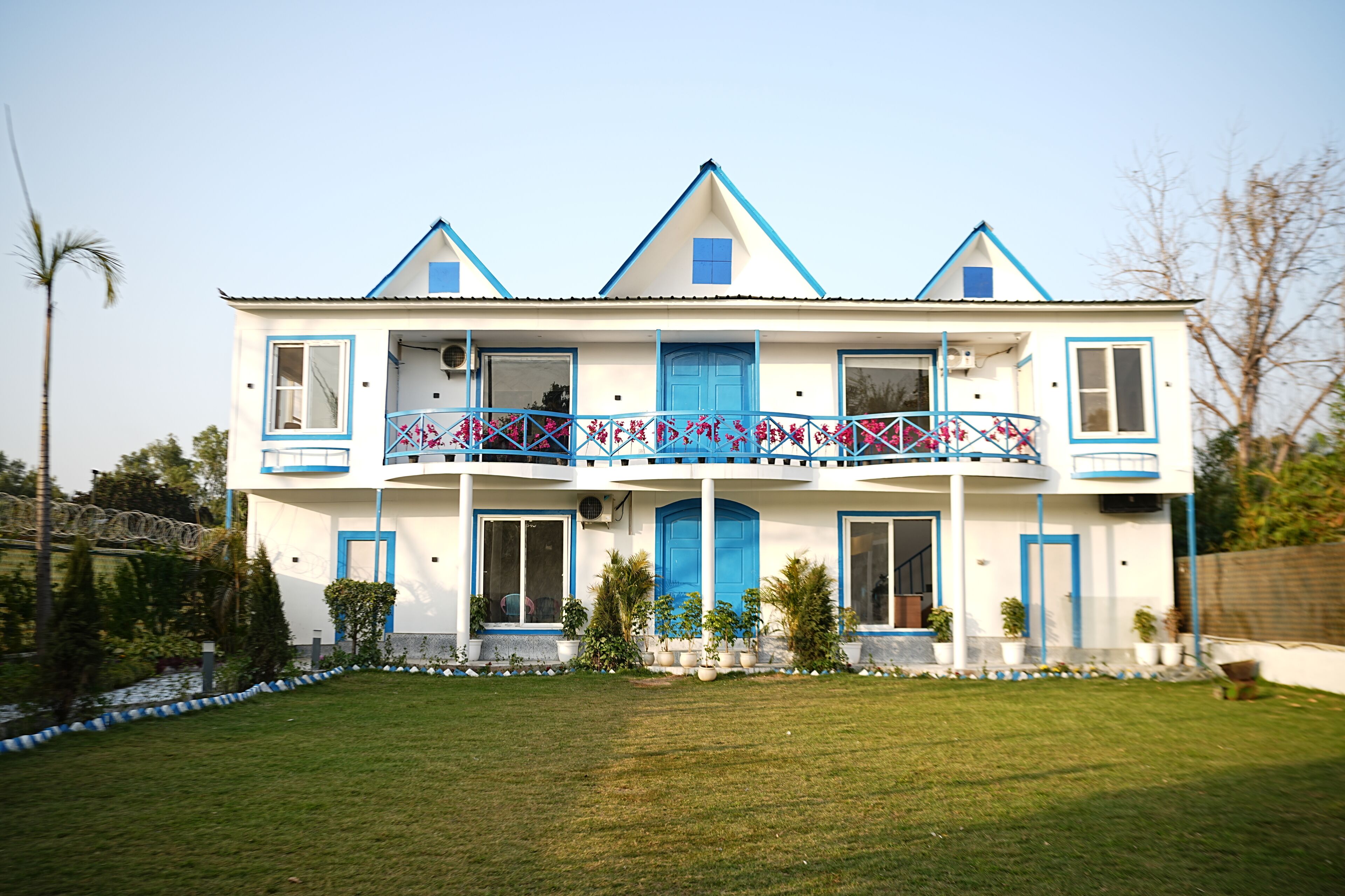 A two-story building with a balcony, windows, and a lawn.