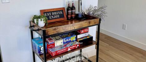 A wooden console table with a sign that reads 'EAT DRINK ENJOY' and two bottles of wine.