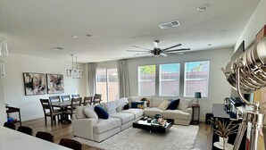 Ein modernes Wohnzimmer mit Sofa, Couchtisch, Essbereich und Deckenventilator.