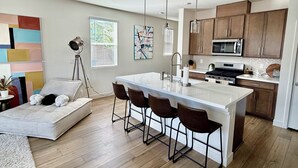 Eine moderne Küche mit Kochinsel, Barhocker und einer Essecke mit einer Couch.