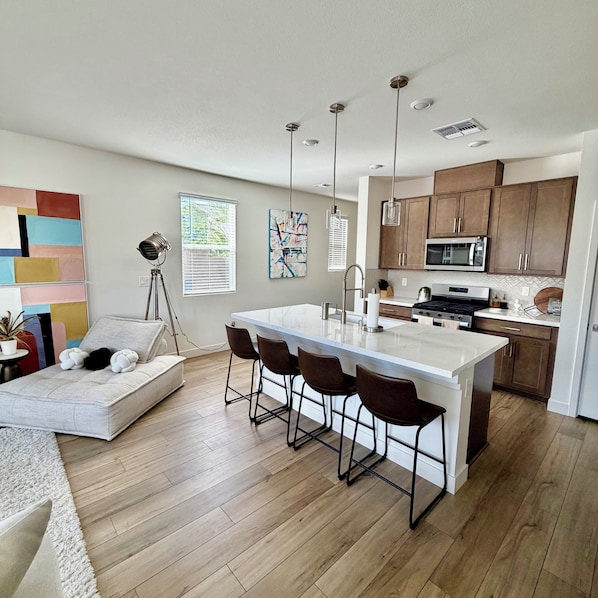 A modern kitchen with a central island, bar stools, and a dining area with a sofa. - Modern Las Vegas Getaway, Close to all the Fun!! (Las Vegas)