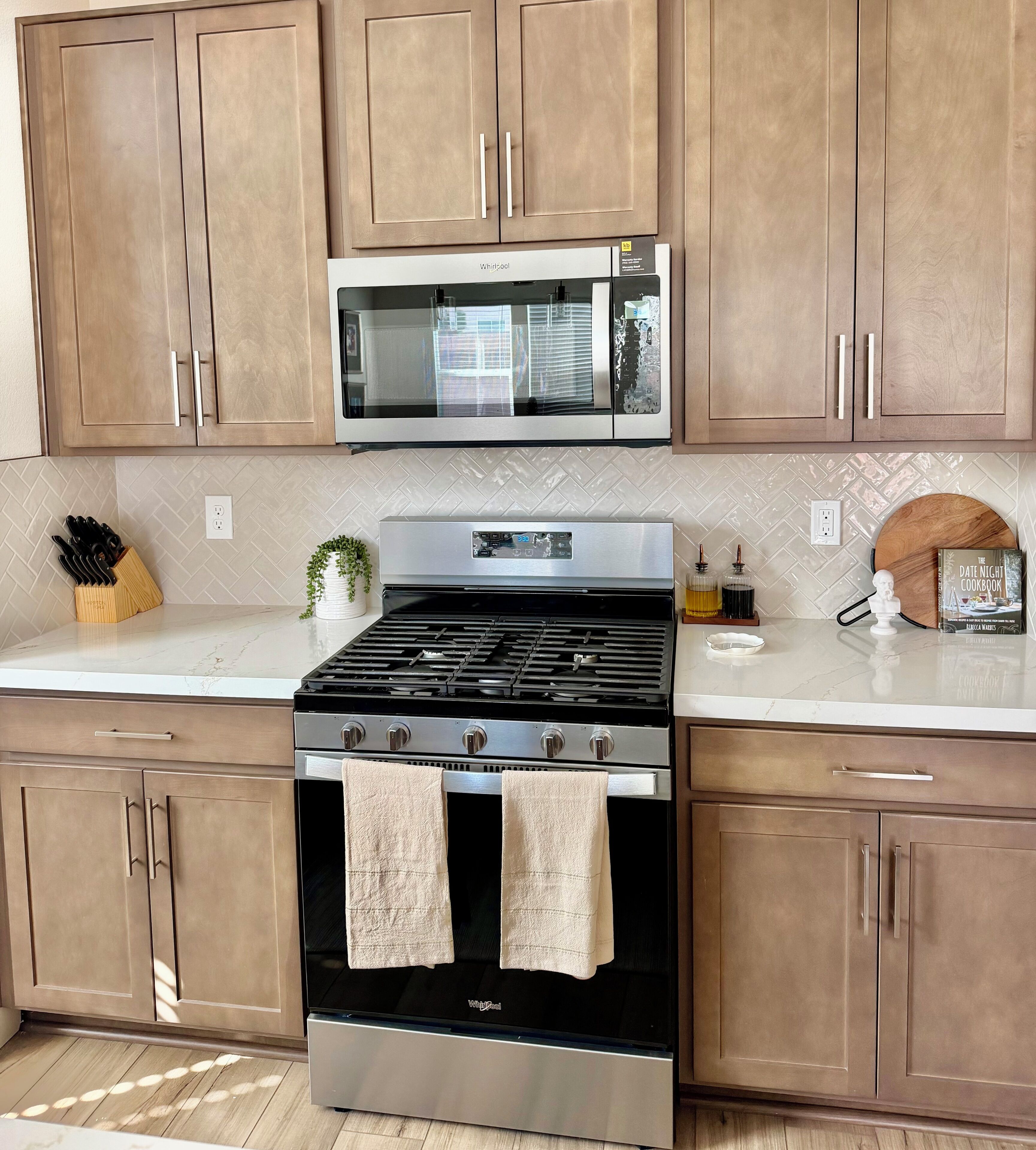 A kitchen with wooden cabinets, a stainless steel stove, a microwave, and a white countertop.