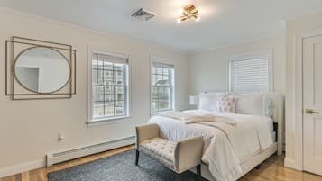 Une chambre à coucher avec un lit, une chaise, un miroir rond et une fenêtre.
