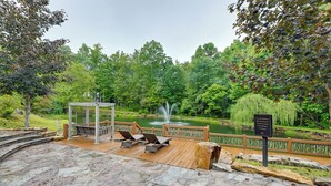A wooden deck with lounge chairs overlooking a pond and a waterfall. - 2BD Mtn Retreat near Nantahala w/ Firepit and Pond (Andrews)