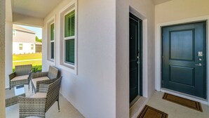 A covered porch with wicker furniture and a dark door. - Groveland Suite w/ Patio: Near Wineries & Trails (Groveland)