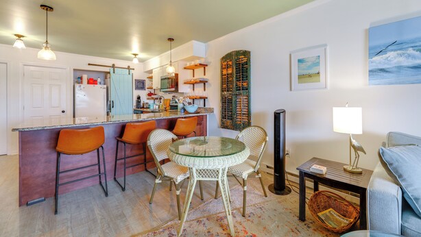 Una cocina moderna con barra, una mesa de comedor con sillas, un televisor y una lámpara.